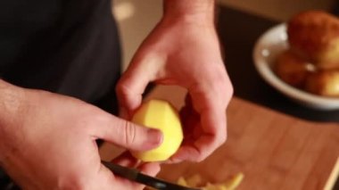 Erkeklerin elleri altın patatesi soyarken ve patates soyacağı ile sebzelerin derisini yüzerken.