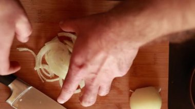 man hands cutting white onion close up in wooden board