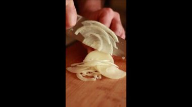 man hands cutting onion on wooden board at home. Vertical video