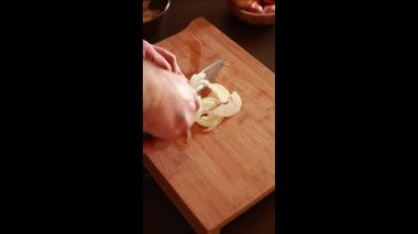 man hands cutting onion on wooden board at home. Vertical video