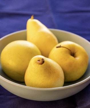 Sarı elmalar ve armutlar bir kase sonbahar atmosferinde kapanıyor.