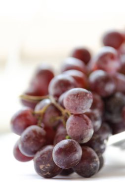 Bir demet üzüm, beyaz arka planda cam kasede kapanıyor.