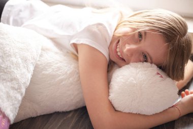 Kız büyük pelüş oyuncakta uyuyormuş gibi yapıyor.