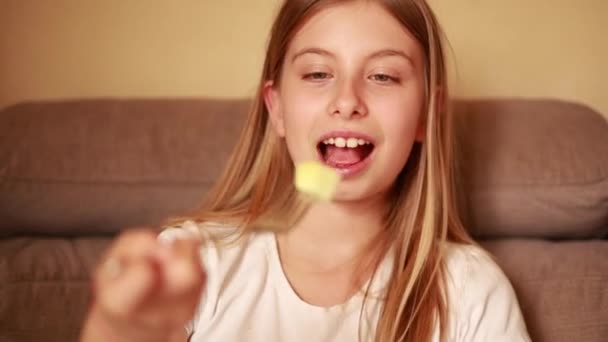 Κορίτσι Τρώνε Μοσχοκάρυδο Στον Καναπέ Και Χαμόγελο — Αρχείο Βίντεο
