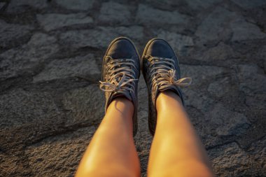 Mavi spor ayakkabılı kadın bacakları. Gün batımı.