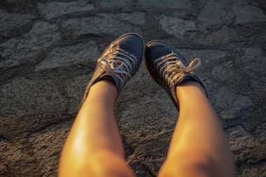 Mavi spor ayakkabılı kadın bacakları. Gün batımı.