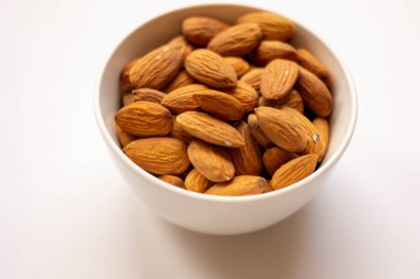 Beyaz arka planda lezzetli bademler olan kase, üst manzara.