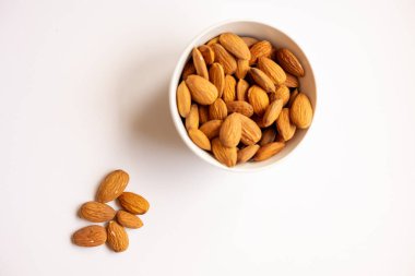 Beyaz arka planda lezzetli bademler olan kase, üst manzara.