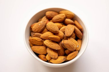 Beyaz arka planda lezzetli bademler olan kase, üst manzara.