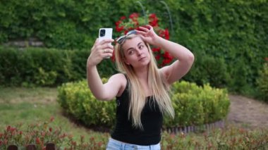 Parktaki videoda selfie çeken sarışın kadın.