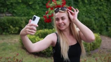 Parktaki videoda selfie çeken sarışın kadın.