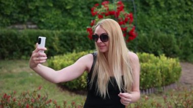 Parktaki videoda selfie çeken sarışın kadın.