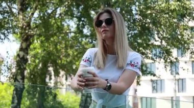 Sarışın kadın dışarıda kahve içiyor.