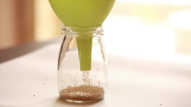  Quinoa 'nın cam bir kavanoza yerleştirilme, organizasyon ve sürdürülebilir gıda depolama sürecini kaydeden video.