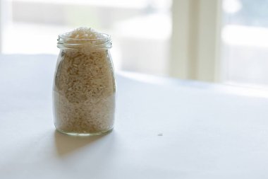 Cam bir kavanozda çiğ beyaz pirinç. Beyaz arka plana yakın.