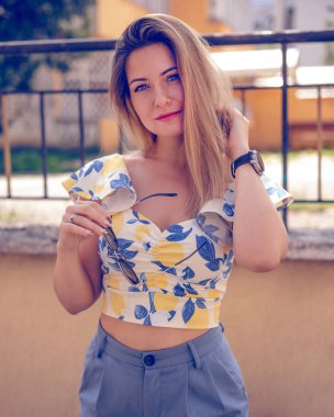 Güneş gözlüklü kadın dışarıda şık yazlık kıyafetler giyiyor.