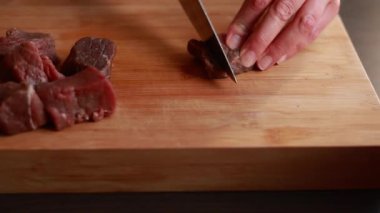 Kadın elleri, yahni için çiğ eti küçük parçalara ayırıyor. Evde yemek pişirmek.