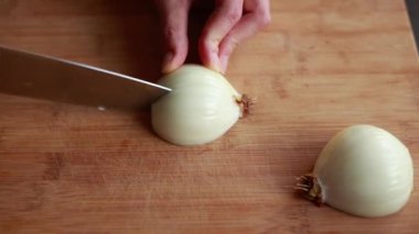 Kadın elleri evdeki ahşap tahtaya yakın çorba yapmak için soğan doğruyor.