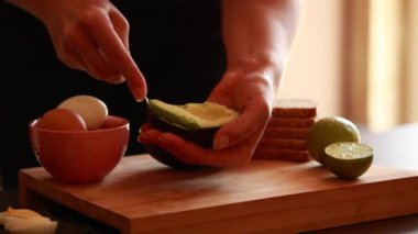 Kadın elleri avokadoyu yemek için hazırlıyor. Evdeki tahta tahtaya yakın dur.