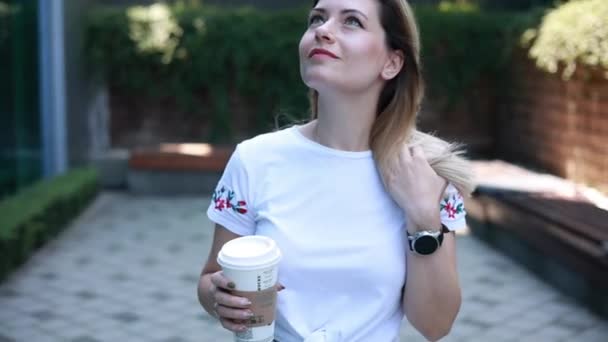 外に出るためにコーヒーを飲みながらカジュアルな服を着た女性 — ストック動画