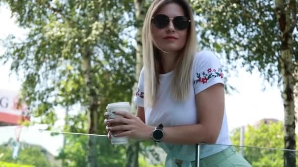 外に出るためにコーヒーを飲みながらカジュアルな服を着た女性 — ストック動画