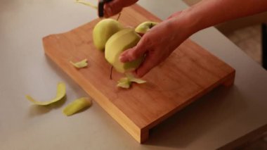 Mutfaktaki kadın elmalı pasta için elma soyuyor.