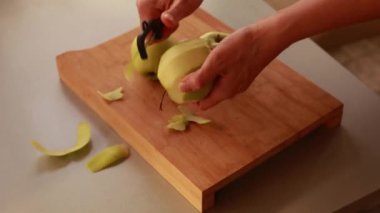 Mutfaktaki kadın elmalı pasta için elma soyuyor.