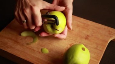 Mutfaktaki kadın elmalı pasta için elma soyuyor.