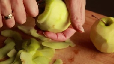 Mutfaktaki kadın elmalı pasta için elma soyuyor.