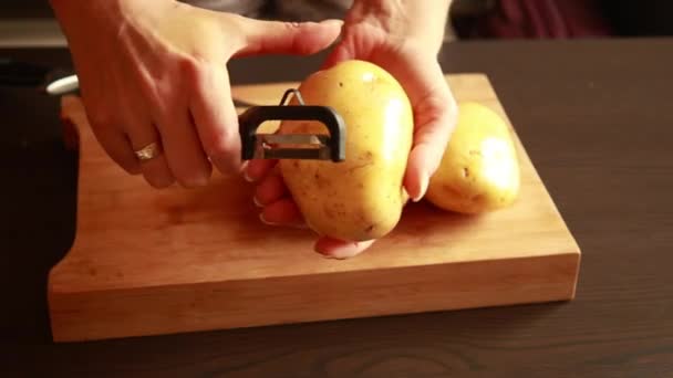 手剥皮土豆 女人用马铃薯剥皮剥去土豆皮 土豆正在准备烹调食物 后续行动 — 图库视频影像