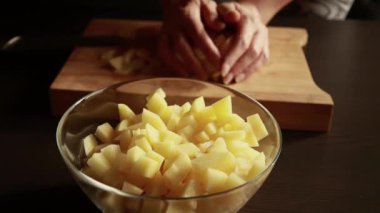 Patates kesmek. Bıçağı kapat, patatesi kes. sebze pişirmek. Yemek hazırlama. Kadın taze patates keser. Ahşap mutfak tahtasının üzerinde olgun patates kesikleriyle kadın eli