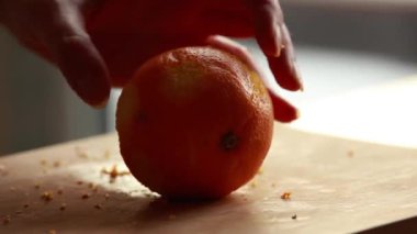 Kadın elleri ahşap tahtada portakal kesiyor.