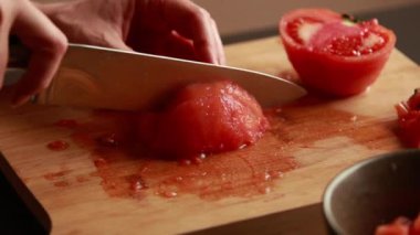 Aşçılık sanatı: kadın elleri kesiyor, doğruyor, domatesleri yakından soyuyor.