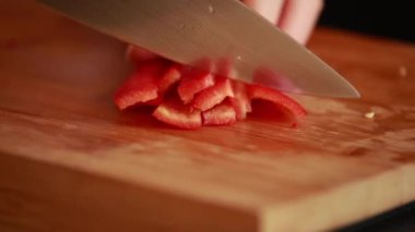 Mutfak inceliği: kadın elleri tahta tahtada taze kırmızı dolma biber kesiyor.