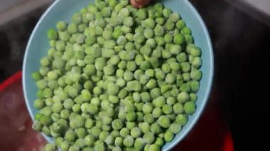 Ev yapımı konfor: yemek yapmak, kırmızı bir tencerede bezelye çorbası hazırlamak.