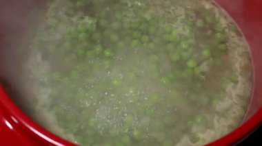 Ev yapımı konfor: yemek yapmak, kırmızı bir tencerede bezelye çorbası hazırlamak.