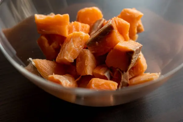 Close-up of raw fresh salmon fillets cut into cubes and presented in a glass bowl, highlighting their freshness and texture