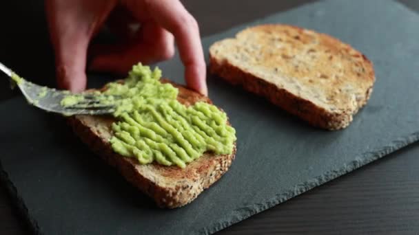 Bir Dilim Ekmeğin Üzerine Kremalı Avokado Döken Birinin Büyüleyici Yakın — Stok video