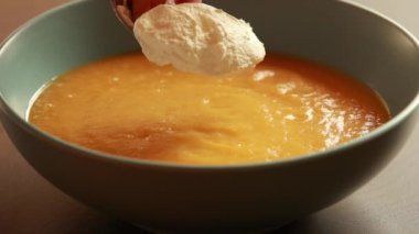  Mavi bir kasede sunulan havuç çorbası ev yapımı yemeğin rahatlığını ve sıcaklığını gösteriyor..