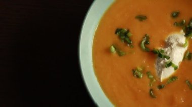  Mavi bir kasede sunulan havuç çorbası ev yapımı yemeğin rahatlığını ve sıcaklığını gösteriyor..