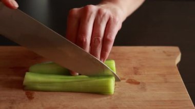 Tahta üzerinde ustalıkla salatalık doğrayan bir kadının ellerini gösteren, gevrek ve ferahlatıcı salata malzemelerinin hazırlıklarını gösteren yakın plan bir video.