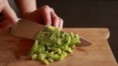 Tahta üzerinde ustalıkla salatalık doğrayan bir kadının ellerini gösteren, gevrek ve ferahlatıcı salata malzemelerinin hazırlıklarını gösteren yakın plan bir video.