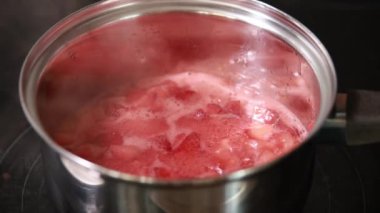Meyve reçeli pişirme, ev yapımı çilek reçeli yapma süreci. Kırmızı tatlı şurup ocağın üstünde kaynıyor. Ev yapımı Çilek Reçeli