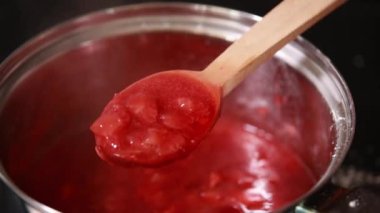 Meyve reçeli pişirme, ev yapımı çilek reçeli yapma süreci. Kırmızı tatlı şurup ocağın üstünde kaynıyor. Ev yapımı Çilek Reçeli