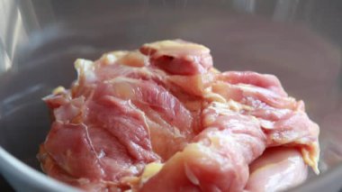 Kadın elleri, bu yakın çekim videosunda baharatı kemiksiz tavuk butlarına güzelce sürterek cam kaseye koyuyor.