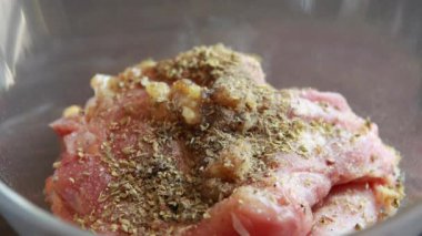 Kadın elleri, bu yakın çekim videosunda baharatı kemiksiz tavuk butlarına güzelce sürterek cam kaseye koyuyor.