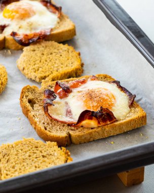 Parşömen kağıdında parmesan olan fırında domuz pastırması ve yumurtalı ekmek.