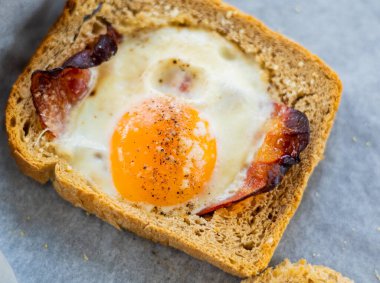 Parşömen kağıdında parmesan olan fırında domuz pastırması ve yumurtalı ekmek.