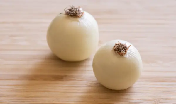 stock image  Two Peeled Onions on Wooden Board Close-Up on Dark Background