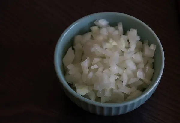 stock image Chopped Onion in a Small Blue Bowl Close-Up on Dark Background